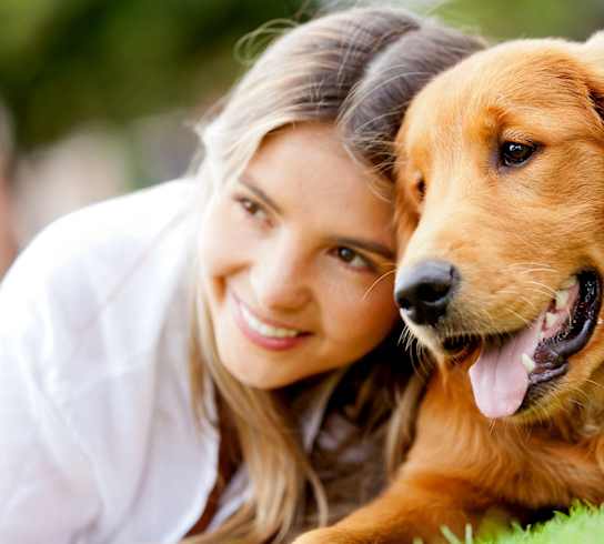 a woman and her dog laying on the grass