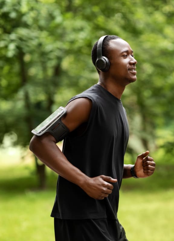 Man Wearing Headphones and Smiling while Jogging