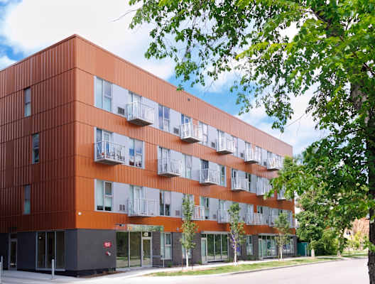 A modern building with orange and white panels and balconies.