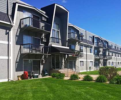 a row of apartments with balconies and green grass