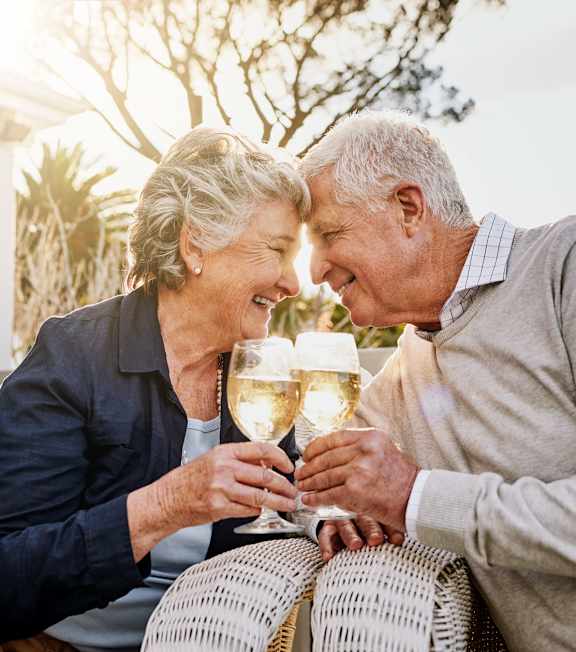 an older couple sitting on a porch with wine glasses in their hands