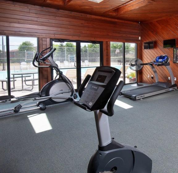 a home gym with a wood paneled walls and ceiling and gray carpeted flooring at Deauville Park Apartments, Monroeville, PA