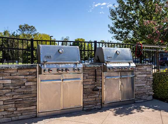 Two stainless steel grills are attached to a stone wall.