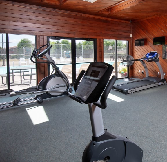 a home gym with a wood paneled walls and ceiling and gray carpeted flooring