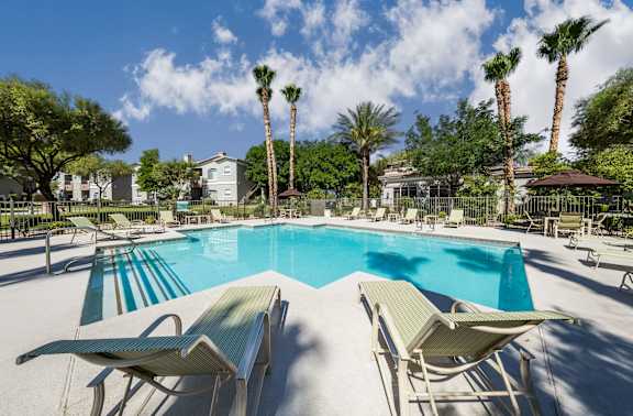A pool with sun loungers and palm trees in the background. at THE PARKSIDE VILLAS APARTMENT HOMES, Nevada
