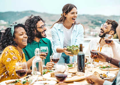 Friends Smiling while Sitting Around Table Drinking Wine