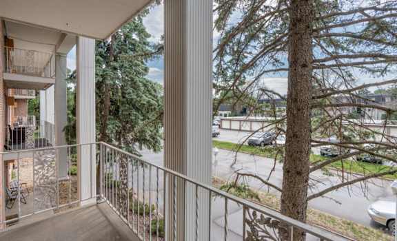a balcony with a view of a tree and a parking lot