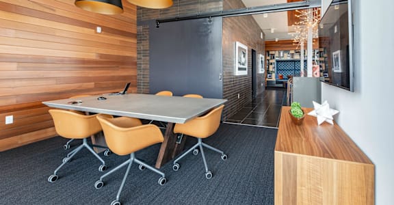a conference room with a long table and four yellow chairs