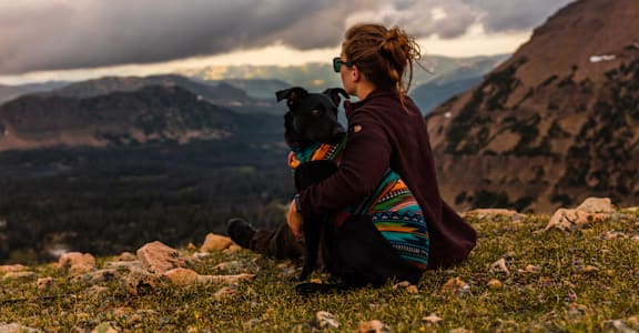 Woman Sitting with Dog Looking at Mountains