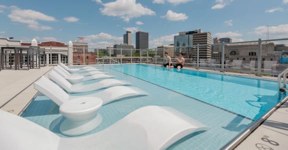 a rooftop pool with lounge chairs and a view of the city