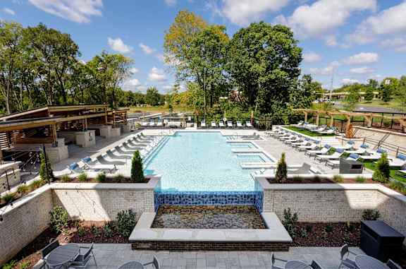 A large outdoor swimming pool surrounded by trees and lounge chairs.
