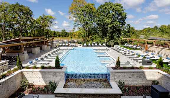 A large outdoor swimming pool surrounded by trees and lounge chairs.