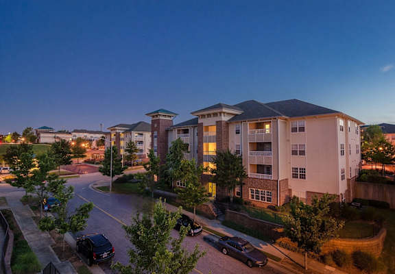 Apartment complex with cars parked in front and trees in the foreground.
