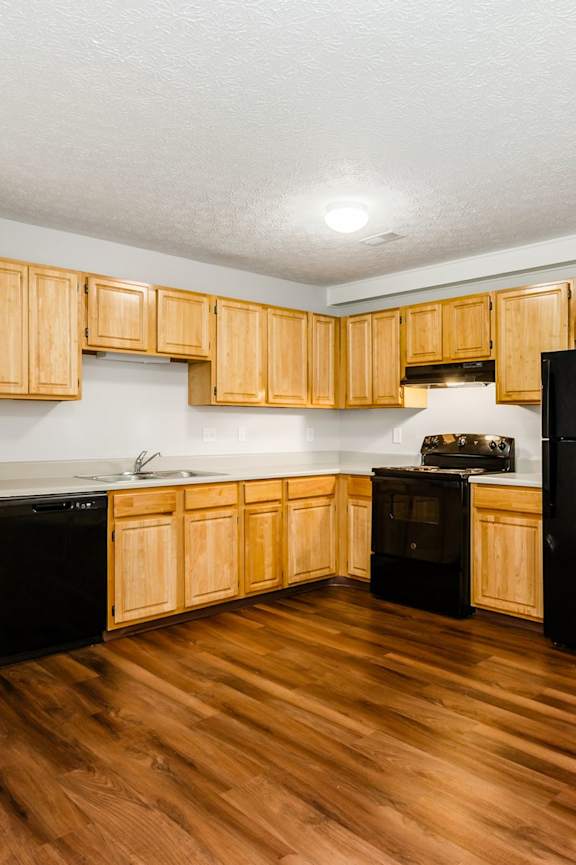 A kitchen with wooden cabinets and black appliances.