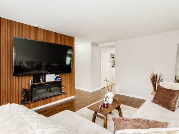 A living room with a white couch and a wooden wall.