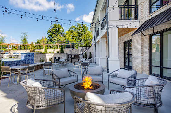 A patio with a fire pit and chairs.