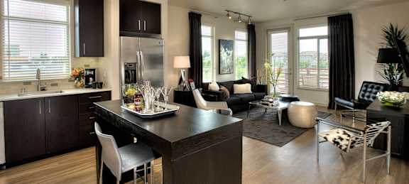 A modern kitchen with dark wood floors and a black island.