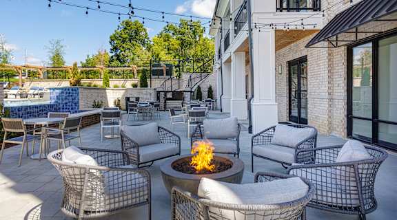 A patio with a fire pit and chairs.