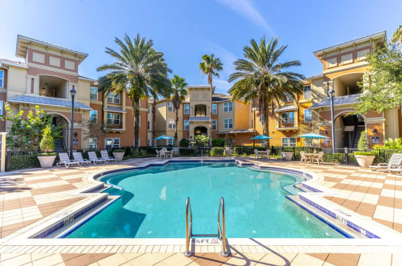 a large pool with palm trees and apartments in the background