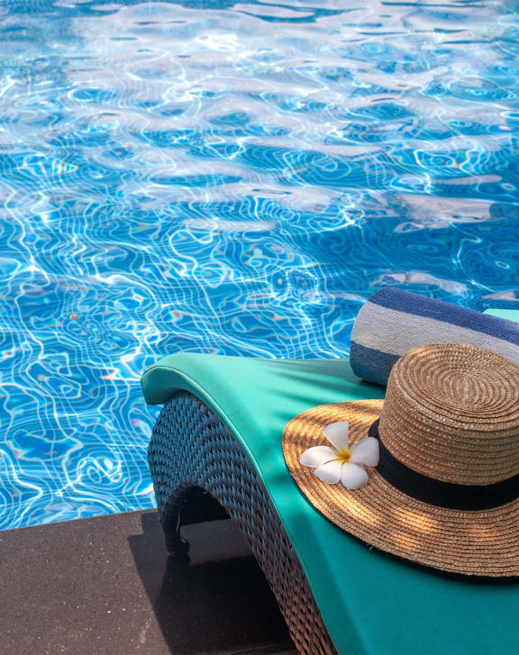 a hat and towels on a chair next to a pool
