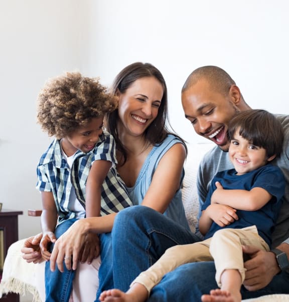 smiling family sitting on a couch in their living room at Hidden Woods, Decatur