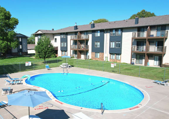 an aerial view of a large swimming pool with lounge chairs and umbrellas in front of