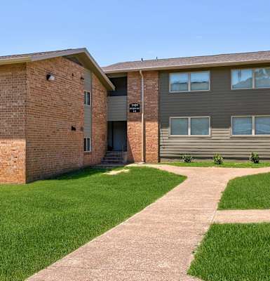 A building with a brick facade and a sign that reads "Apartments" on the right side.