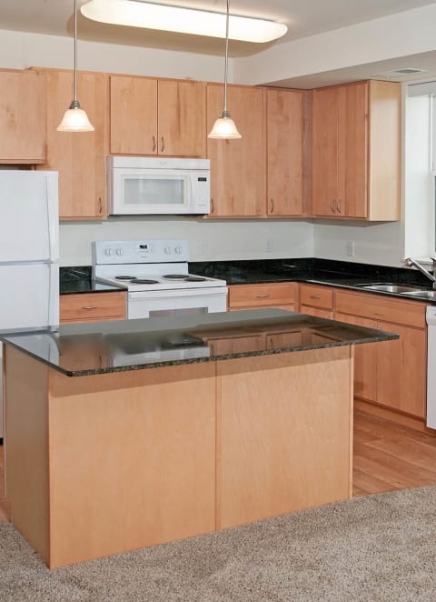 a kitchen with an island and white appliances at The Cavanagh 55+ Apartments, Crystal, MN 55429
