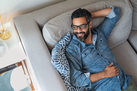 Man Smiling while Laying on Couch