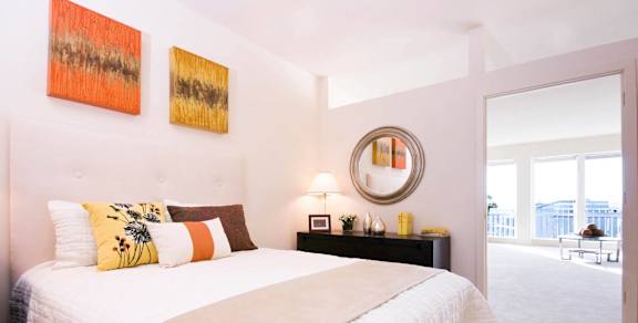 A bedroom with a large bed and two paintings on the wall.
