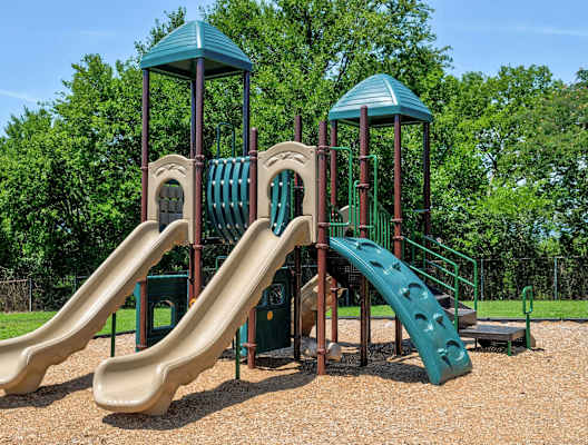 A playground with a green slide and brown slide.