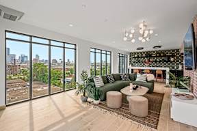 A living room with a green couch and a view of the city.