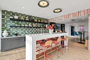 A kitchen with a white counter and red chairs.