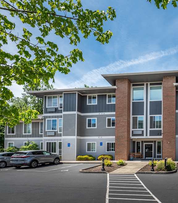 A large apartment building with a parking lot in front. at Fairview Village Apartments, Fairview, OR, 97024