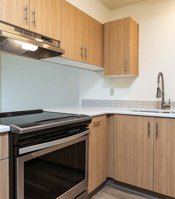 A kitchen with wooden cabinets and a stainless steel oven.