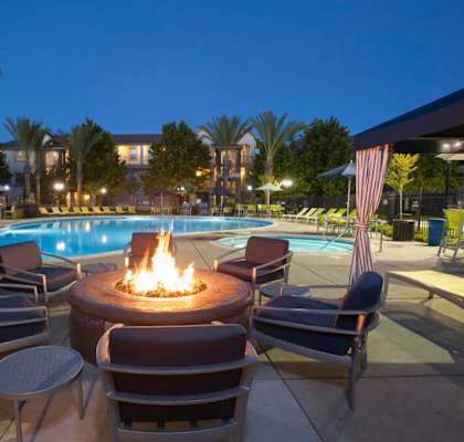 A fire pit sits in the middle of a pool surrounded by chairs.