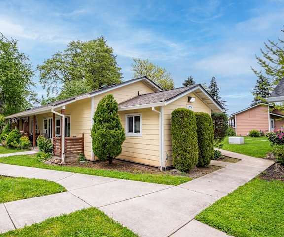 a small yellow house with a sidewalk in front of it