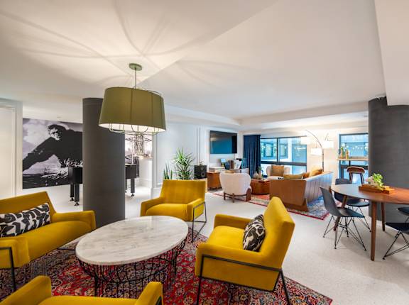 A modern living room with yellow chairs and a white table.