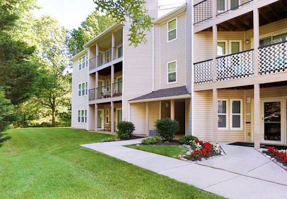 A building with a balcony and a green lawn in front.