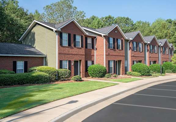 A row of red brick houses with green lawns in front.