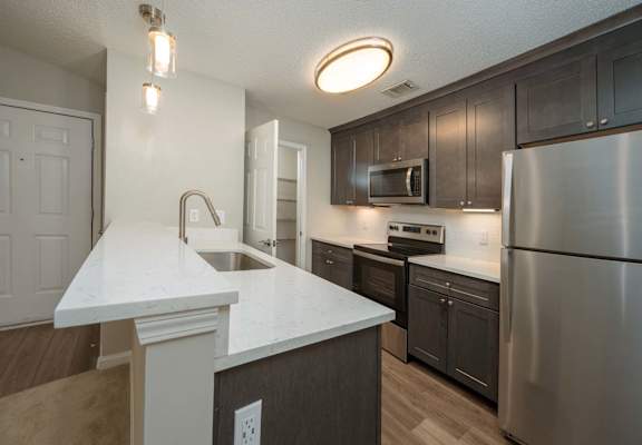 A kitchen with a white countertop and stainless steel appliances.