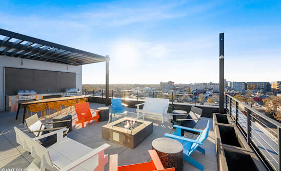 A rooftop patio with a variety of seating options and a view of the city.