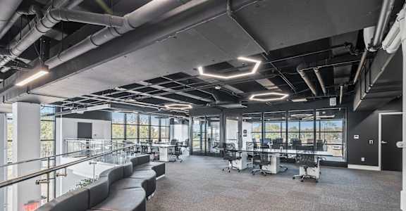 A modern office space with black leather seating and large windows.