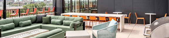 a rooftop patio with green couches and chairs and a table with chairs