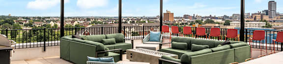 a rooftop patio with green couches and chairs and a view of the city