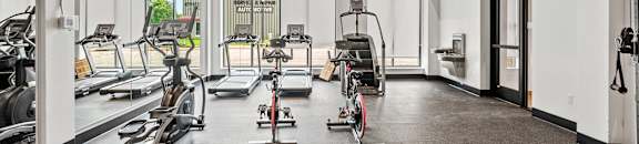 a fitness room with treadmills and other exercise equipment
