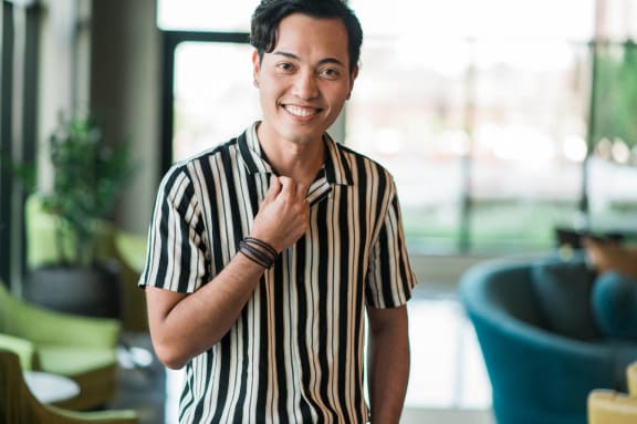 a woman in a striped shirt smiling with her hand on her neck
