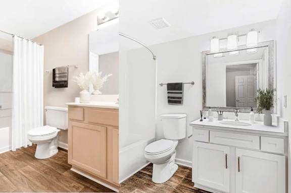 A white bathroom with a toilet, sink, and mirror.