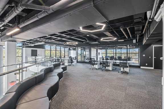 A modern office space with black leather seating and large windows.