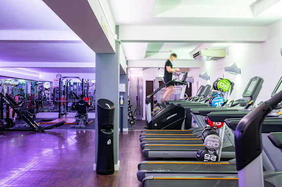 A gym with a woman running on a treadmill.